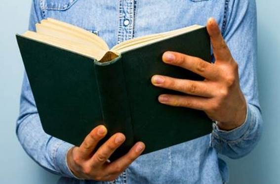 A person holding a book  AI-generated content may be incorrect.Una fotografía que enfoca muy de cerca manos varoniles que sostienen una Biblia abierta.